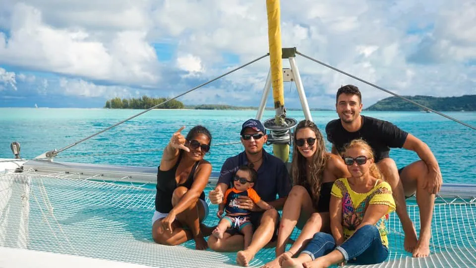 Famille allongée sur les filets du catamaran au-dessus du lagon